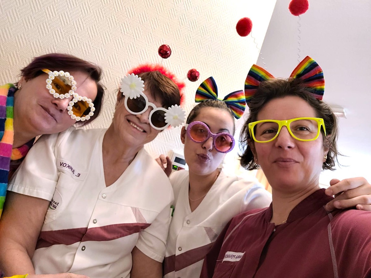Vier Personen in weißen Uniformen tragen bunte Sonnenbrillen und Accessoires wie Schleifen und Hüte.